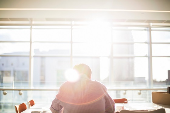 Person with back to camera sitting at desk with a bright sun flare