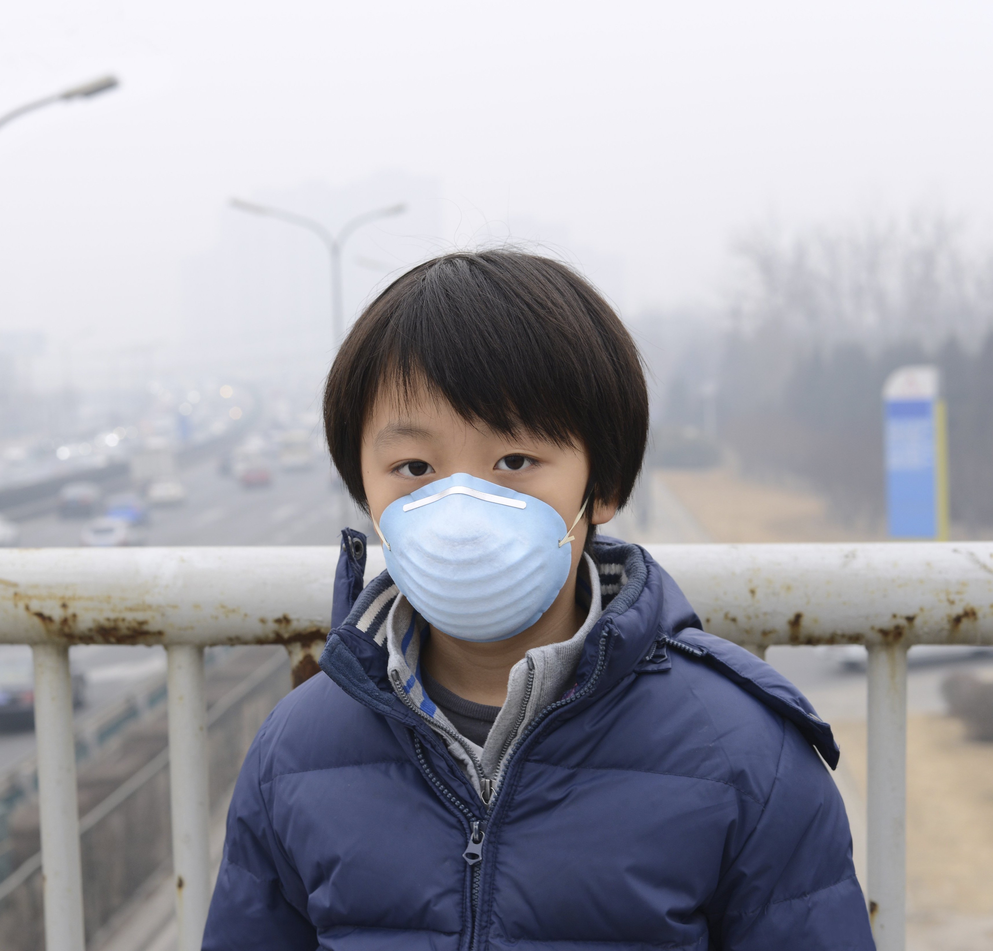 Boy wearing mask in China with polluted air behind