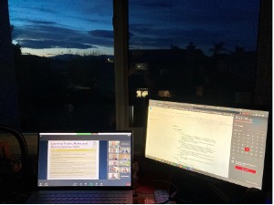 image of two computer screens on a desk in front of a window and the caption "Attending Class Across Time Zones
(Sarah Kuang)"
