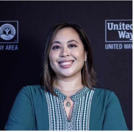 Image of a person with shoulder length hair and wearing a teal and white blouse, smiling